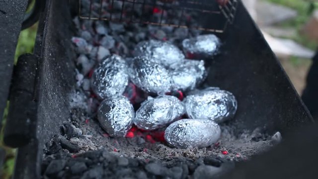 Close up of bonfire with orange and yellow flames and firewood and Baked potatoes covered with aluminum foil, Lag Baomer Jewish holiday bonfire celebration tradition of roasting Potatoes in fire