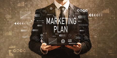 Marketing plan with businessman holding a tablet computer on a dark vintage background