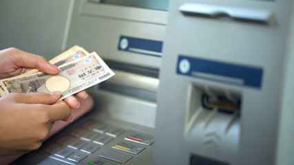 Female getting Japanese Yen from automatic teller machine, cash withdrawing