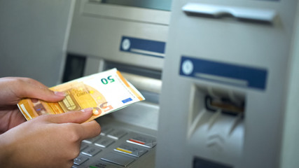 Woman getting euros from automatic teller machine, cash withdrawing, banking