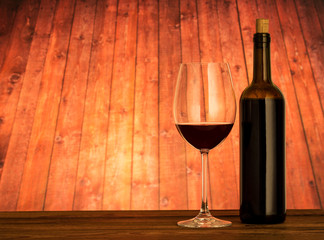 Glass and bottle of red wine on table