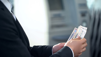 Male counting Yens withdrawn from ATM, good service, business trip to Japan