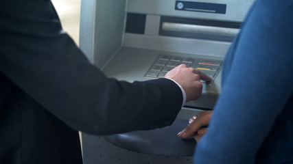 Obraz premium Female bank employee showing new client how to work with ATM, good service