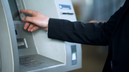 Naklejka na ściany i meble Client entering pin code on ATM to receive money, banking services, withdrawing
