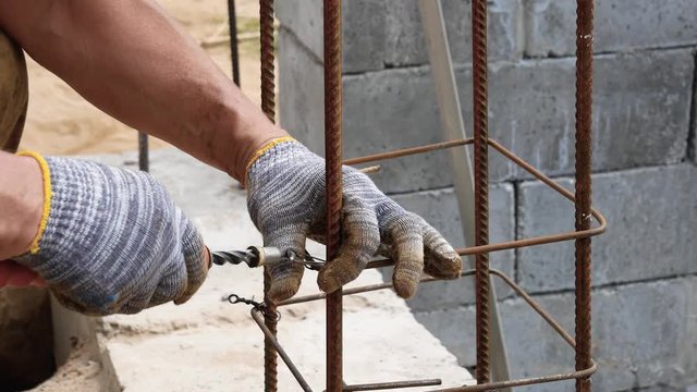 Hands Builder In Dirty Gloves Tied Steel Wire On Rebar Tool On Construction Site