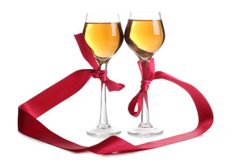 Wine glasses and a red ribbon on white background