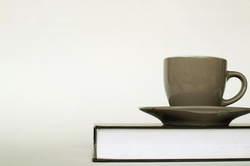 Coffee cup on book on white background.