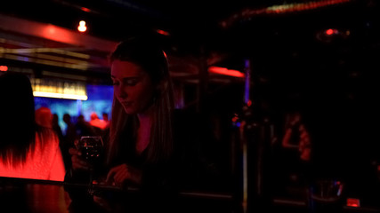 Obraz premium Upset lonely lady drinking wine at bar counter in night club, life problems