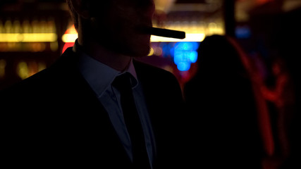 Drunk businessman smoking cigar in elite bar in evening after hard workday