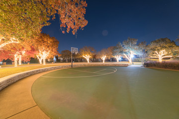 Colorful Christmas and New Year celebration lighting at public park with basketball court near...