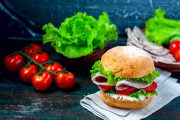 Homemade sandwich with ham and vegetables on wooden background