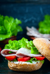 Homemade sandwich with ham and vegetables on wooden background