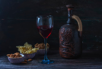 Ceramic jug for wine , cheese, nuts on a wooden board, background.