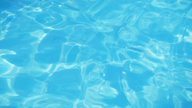 Ripple on blue water in the pool with light reflections.
