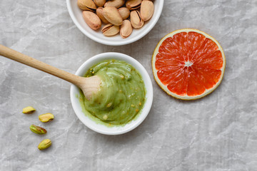 Healthy food, pistachio paste, peeled and unpeeled salted pistachios, grapefruit, wooden spoon on a light background. Components for cooking.