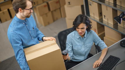 Female Inventory Manager Scans Cardboard Box and with Barcode Scanner, Male Worker Holds Package....