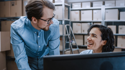 Male and Female Warehouse Inventory Managers Talking, Using Personal Computer and Checking Stock....