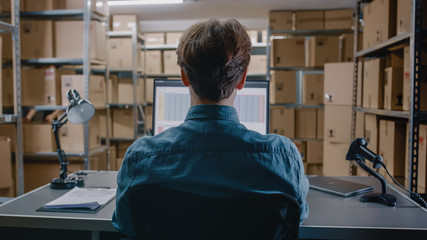 Warehouse Inventory Manager Works with a Spreadsheet on a Personal Computer while Sitting at His...