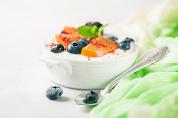 Healthy food, snacks or breakfast. Homemade Greek yogurt with blueberries, blackberries, persimmons and mint. On a concrete stone table.