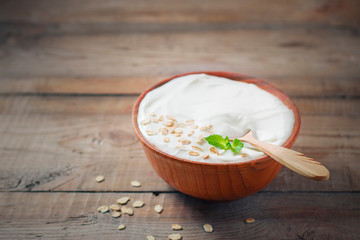 Greek yogurt in a wooden bowl on a rustic wooden table.