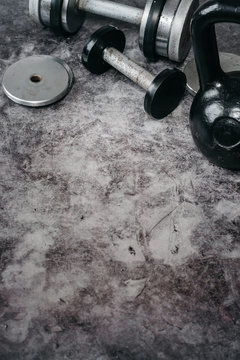 Fitness or bodybuilding concept background. Old iron dumbbells and Kettlebell on grey, conrete floor in the gym.  Top view. Healthz lifestyle.