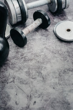 Fitness or bodybuilding concept background. Old iron dumbbells and Kettlebell on grey, conrete floor in the gym.  Top view. Healthz lifestyle.