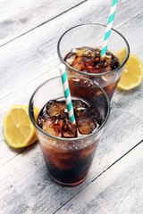 Softdrink with ice cubes, lemon and straw in glass