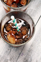 Softdrink with ice cubes, lemon and straw in glass