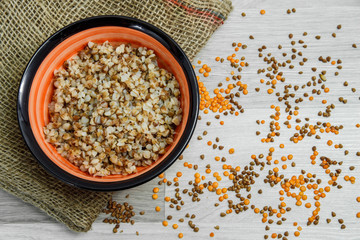 Buckwheat porridge in a plate on a light gray wooden background. View from above.
