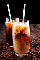 Ice coffee on a rustic table with cream being poured into it showing the texture and refreshing look of the drink
