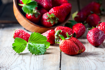 Fresh strawberries in a wooden bowl on a wooden background.