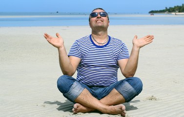 man meditating on the beach