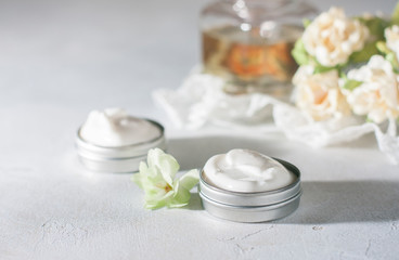 Fototapeta na wymiar cosmetic cream with flowers on a light stone background.