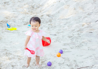 Closeup cute girl play with sand and toy on beach textured background with copy space