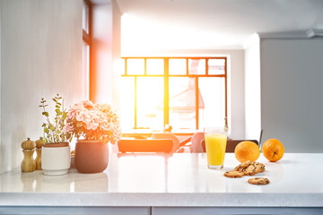 Appetizing sweet orange juice and one drinking glasses standing on a white table in the kitchen for...