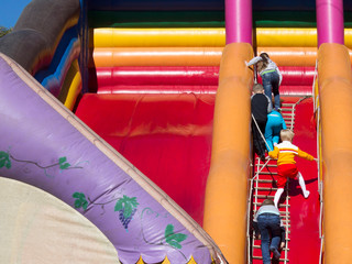 Fototapeta na wymiar Children climb an inflatable slide. Adults are watching them.