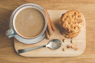 cinnamon sticks, cookies with nuts and a cup of cappuccino/cinnamon sticks, cookies with nuts and a cup of cappuccino on a wooden tray. Top view