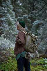 Fototapeta premium Stylish hipster girl in hat in autumn forest. Traveler woman exploring woods. Travel and adventure concept. Expedition vacation, space for text