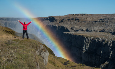 Happy tourist on canyon edge and rainbow near