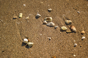 sea shore waterfront district of wet stones on sand background texture near weaves with empty space for copy or text 
