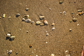 sea shore waterfront district of wet stones on sand background texture near weaves with empty space for copy or text 