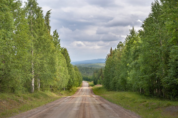 Fototapeta na wymiar A beautiful panoramic macadam road through the forest in Finland. Photo taken August 2017, Lapland, Finland.