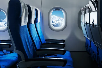 Foto op Plexiglas Lege vliegtuigstoelen. Blauwe lucht en wolken in het raam. Vliegtuig interieur © Ivan Kurmyshov