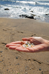 Woman hand holding glass jewels taken on glass beach, Kauai USA