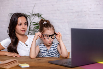 A young mother with little daughter are shopping on the Internet at personal computer