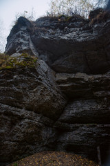 Autumn landscape with the dark rocks, surrounded by autumn forest in the fog, near the river. The concept of travel in the wild, survival.