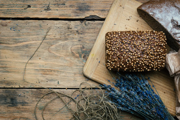 Baked homemade rye dark bread with coriander seeds and lavender on rustic wooden table background. Copy space.