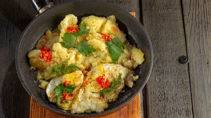Homemade Fried Potatoes and Omelettes in a Frying Pan. On an old black wooden table