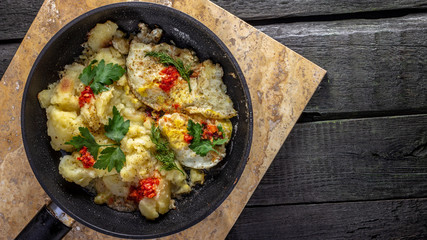 Homemade Fried Potatoes and Omelettes in a Frying Pan. On an old black wooden table