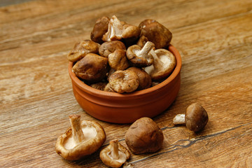 Fresh shiitake mushroom on wooden table, close-up photo in rustic ambient with low light